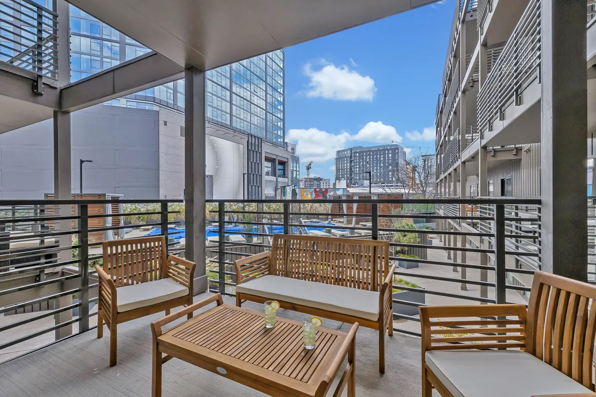 A private outdoor seating area with a stunning city view seen through glass railings. The setup invites relaxation and socializing, with decorative planters adding a touch of greenery and comfort.
