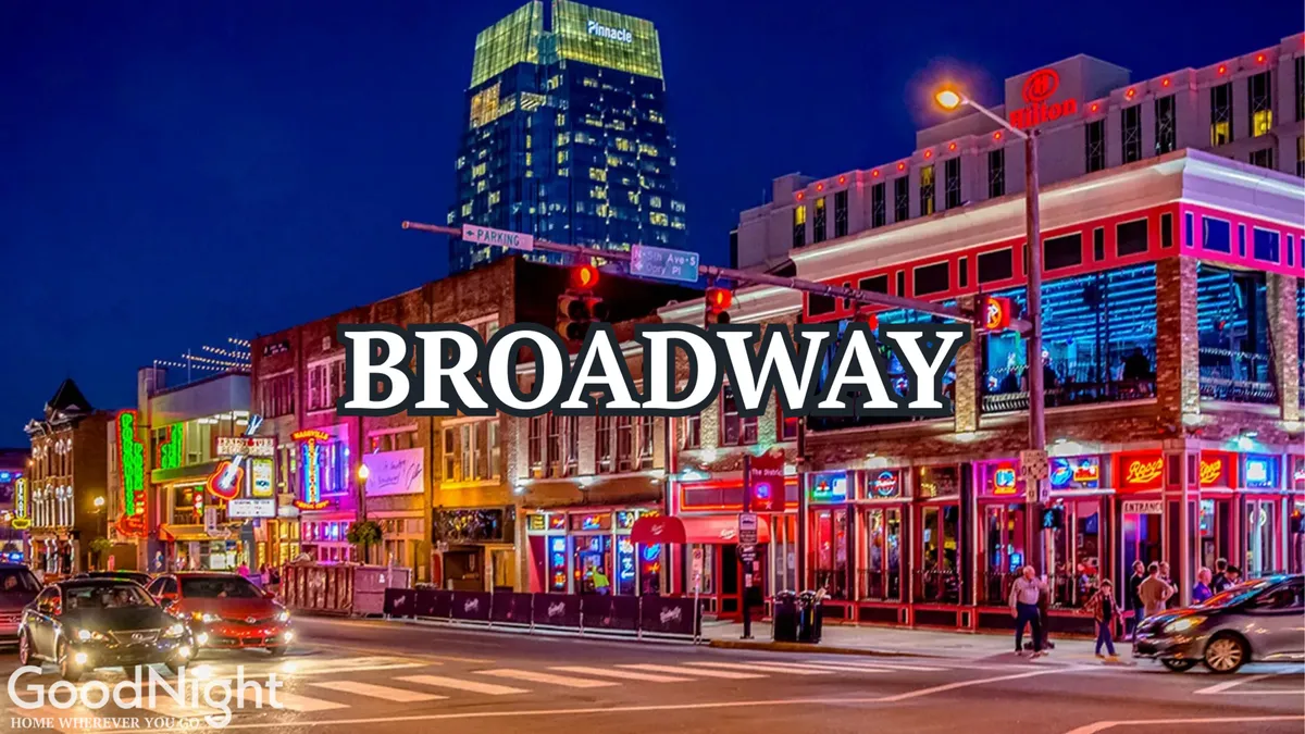 A vibrant nighttime street scene on Nashville's Broadway, overflowing with bright neon signs, bustling traffic, crowds of people, and prominent buildings. The atmosphere radiates excitement and energy, capturing the heart of Nashville's legendary nightlife.